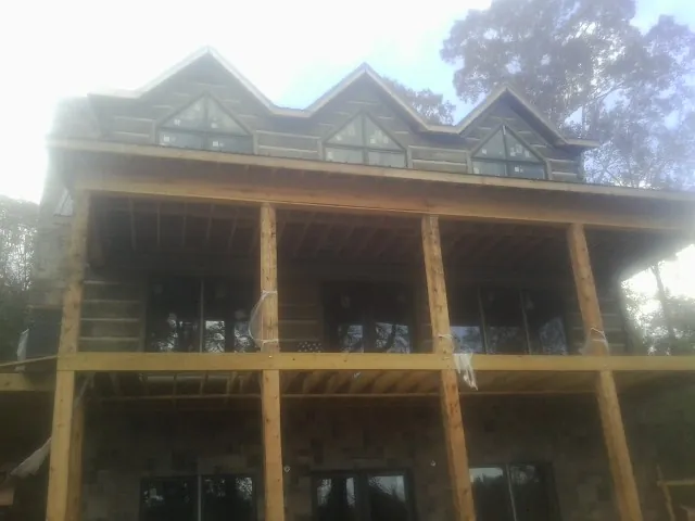 Dormers and porch framing on a large log home under construction — Roof Coating work by our crew in Whitefield