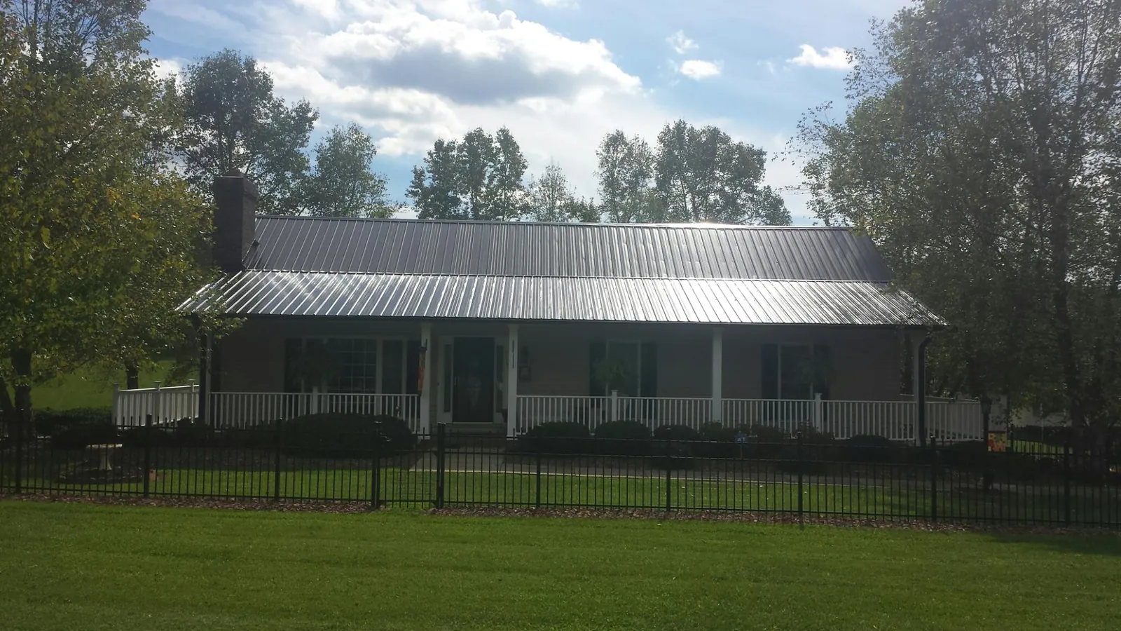 Gray metal roof on a brick ranch with a full width front porch — Gutter Guard Installation work by our crew in Whitefield
