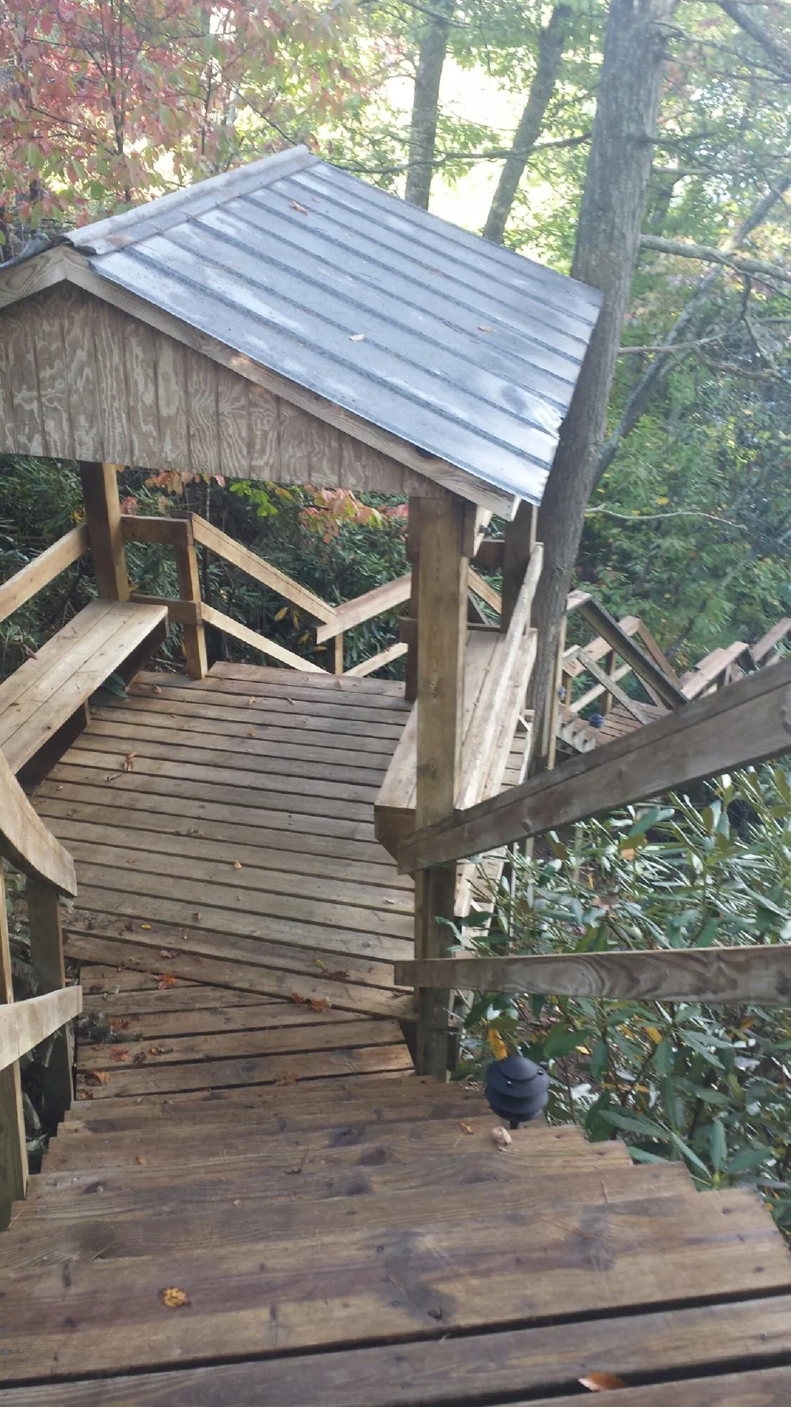 Metal roofed shelter over wooden steps on a wooded walkway — Skylight Repair & Installation work by our crew in Whitefield